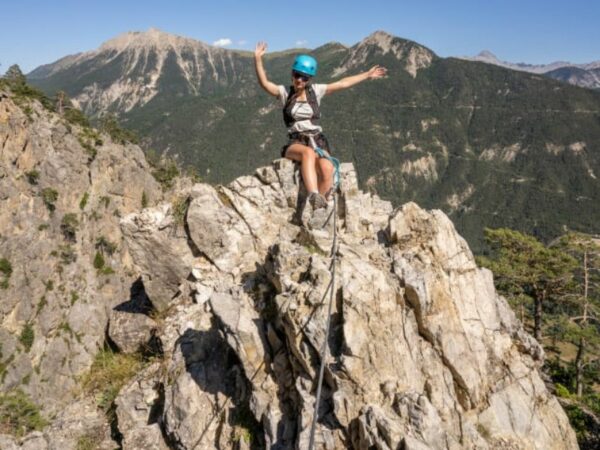 Une serre chevalier activites moins connue : une jeune femme escalade un sommet de montagne en été.