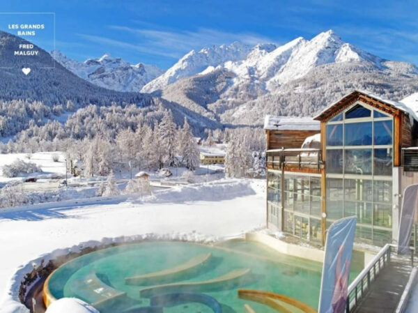 maison alliey-les grands bains établissement thermal, des piscines extérieures chauffées dans un décor de montagnes enneigées.