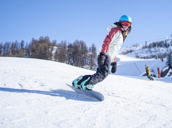 Une femme qui surfe sur le domaine skiable de serre chevalier par une journée ensoleillée.